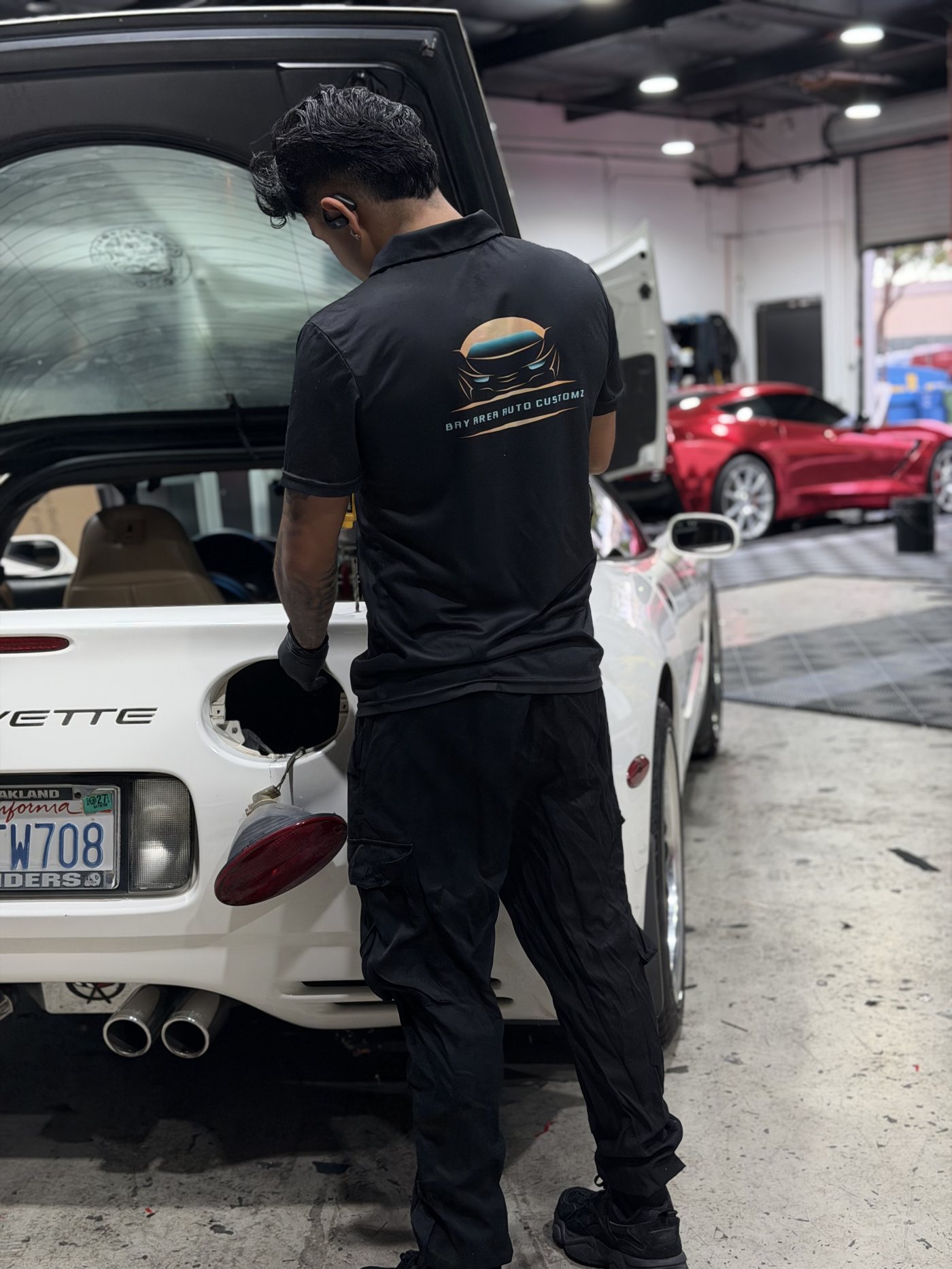 Sergio at the Corvette with another customer build on the lift behind him
