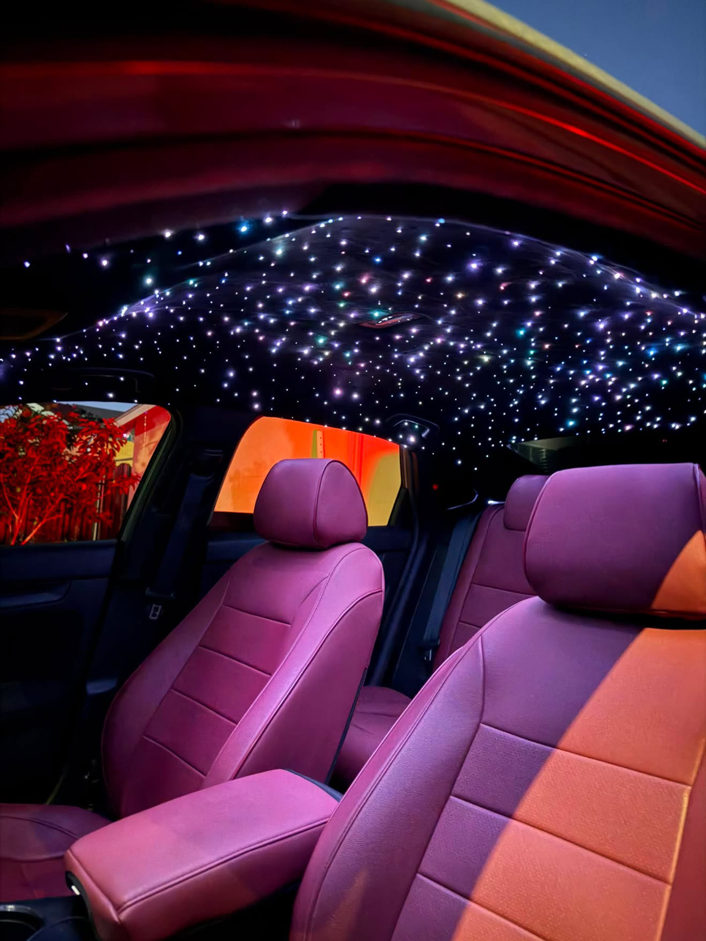 Multicolor starlight headliner twinkling in blues, violets and warm tones above burgundy seats