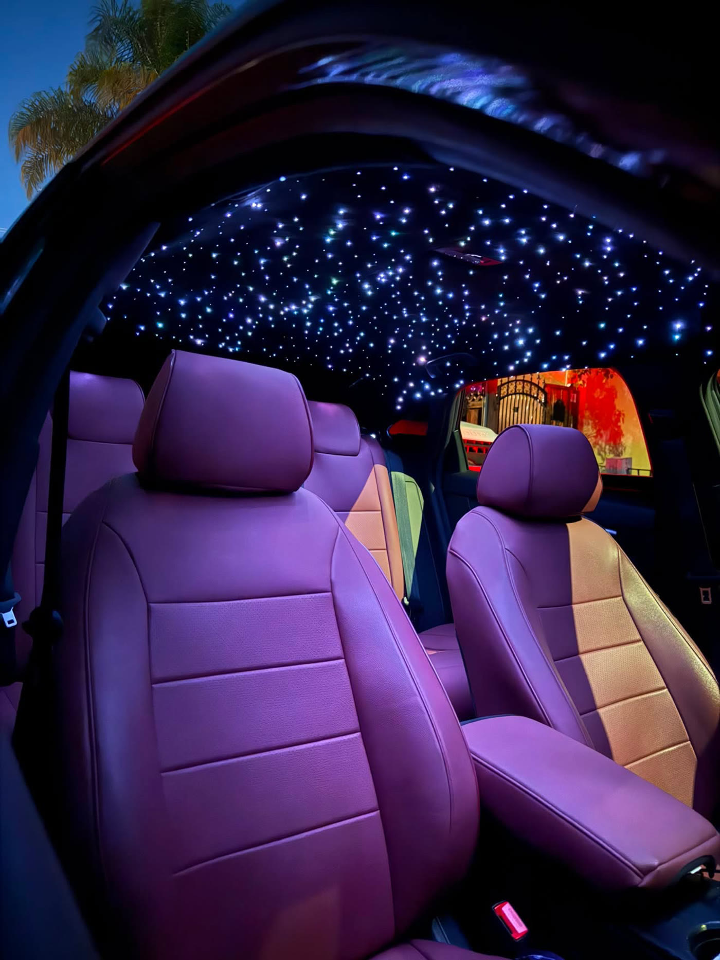 Dense white starlight headliner glowing over a plum leather cabin at dusk