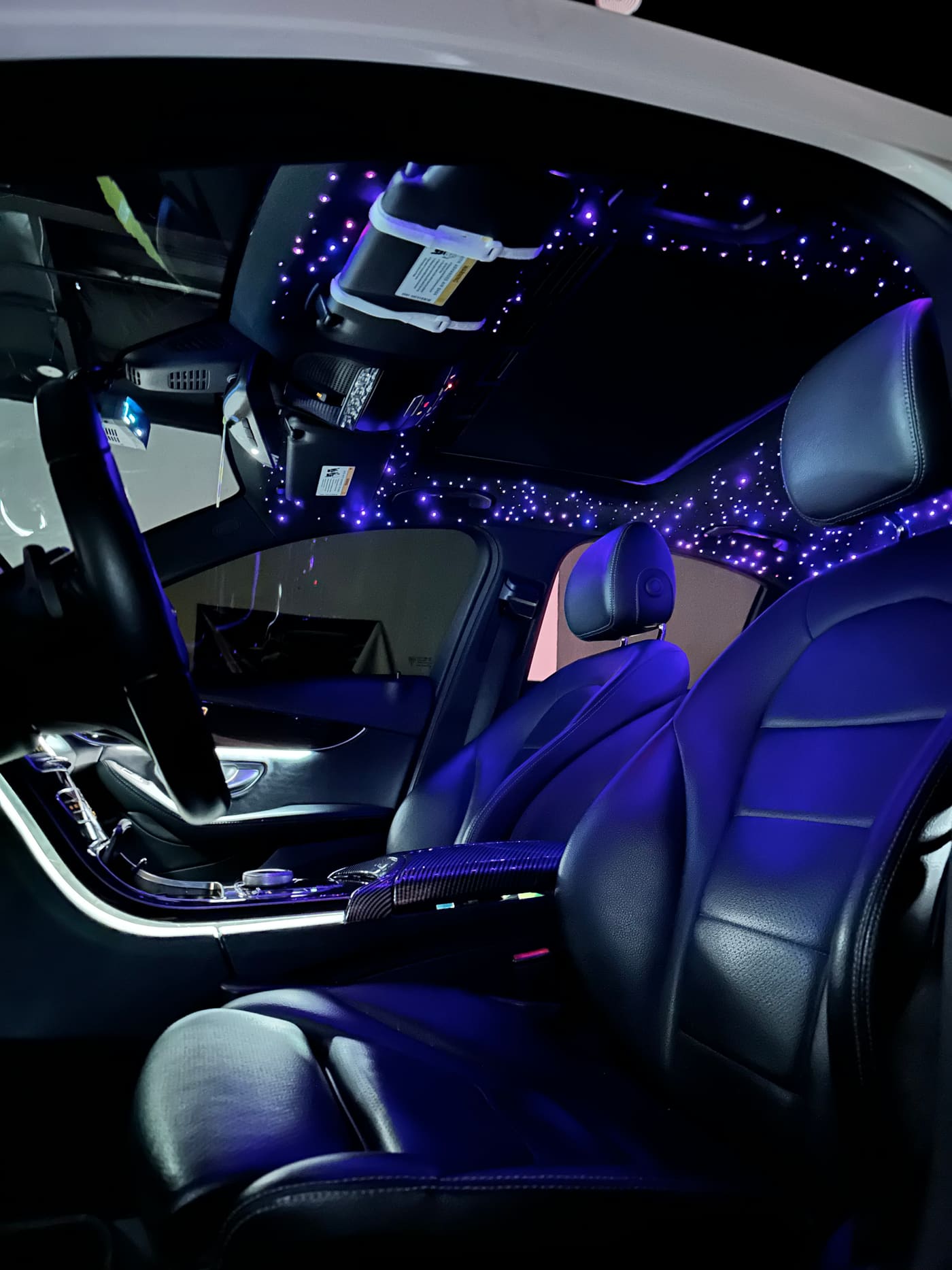 Purple starlight headliner glowing above the front seats of a Mercedes C-Class